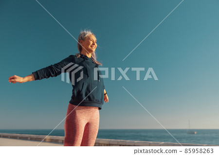 Adult slender woman standing by the waterfront Adult slender woman standing by the waterfront 85958263