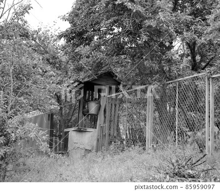 Old well with iron bucket on long forged chain for clean drinking water 85959097