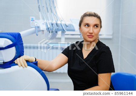 a female dentist in a black uniform at her workplace in the cab of the clinic. a female dentist in a black uniform at her workplace in the cab of the clinic. 85961144