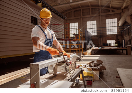 Smiling male carpenter using woodworking machine in workshop 85961164