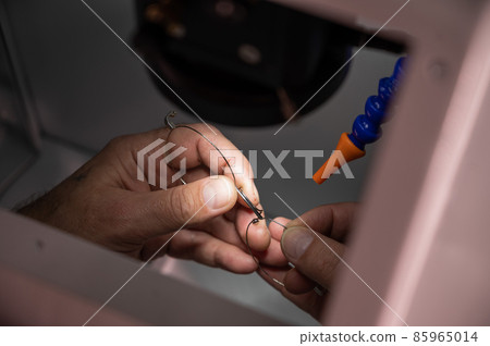 The technician solders the metal frame of the glasses. 85965014