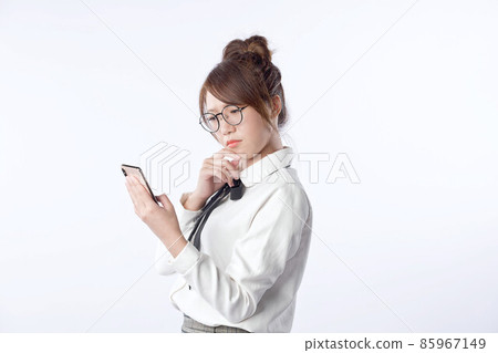 Portrait of a young girl who is holding a cell phone and worry about something with isolated white background. Negative human emotion face expression feeling. 85967149