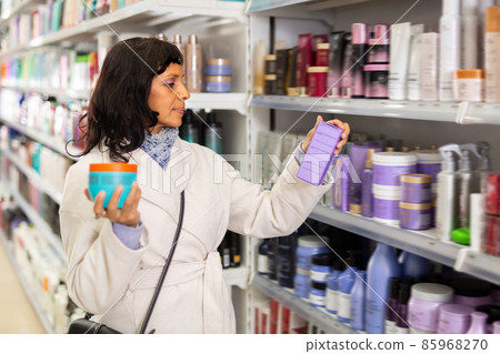 Adult Latina choosing haircare cosmetics in specialized boutique 85968270