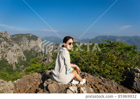 Asian woman with sunglasses sit on the top of the mountain. 85969932