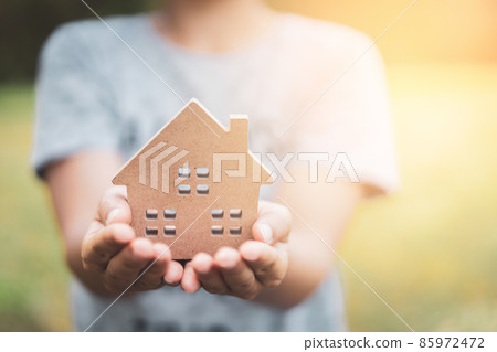Small home model on woman hand. Family life and business real estate concept. Small home model on woman hand. Family life and business real estate concept. 85972472
