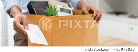Resignation Concept The male officer standing, putting his box of his belongs on the desk and handing the white letter to someone 85972838
