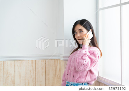 年輕女子在窗邊打電話 85973192