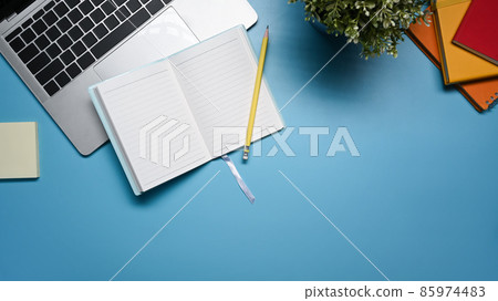Top view notebook, laptop computer, sticky note and potted plant on blue background. 85974483