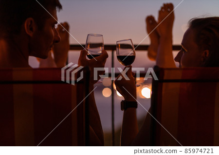 Romantic couple talking and have wine at sea view terrace at sunset. Valentine day image Romantic couple talking and have wine at sea view terrace at sunset. Valentine day image 85974721