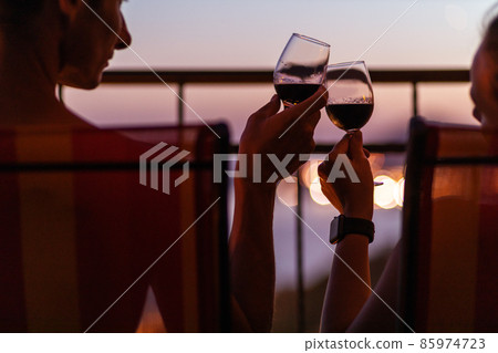 Silhouette of couple drinking wine at the sea view terrace in the evening. Valentine day image Silhouette of couple drinking wine at the sea view terrace in the evening. Valentine day image 85974723