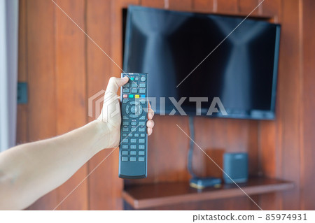 hand using remote controller for adjust Smart TV inside the modern room at home or luxury hotel 85974931