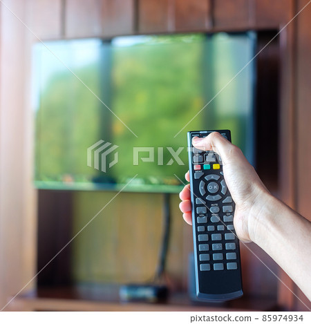 hand using remote controller for adjust Smart TV inside the modern room at home or luxury hotel 85974934