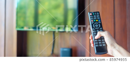 hand using remote controller for adjust Smart TV inside the modern room at home or luxury hotel hand using remote controller for adjust Smart TV inside the modern room at home or luxury hotel 85974935