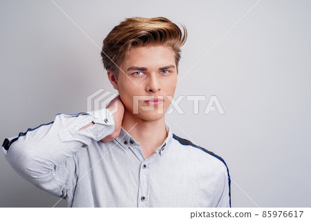 Studio portrait of handsome young guy wearing shirt while looking at camera. Stylish man's haircut Studio portrait of handsome young guy wearing shirt while looking at camera. Stylish man's haircut 85976617