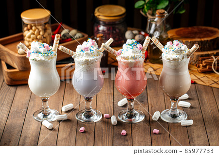Four glasses of sweet milkshakes with biscuits 85977733