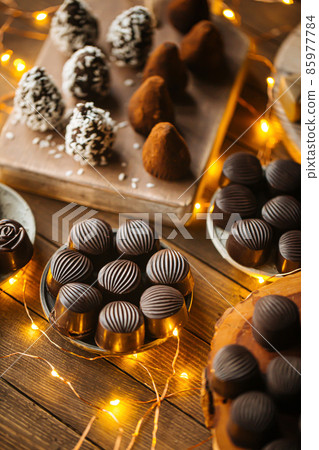 Assorted chocolates on wooden table with garland Assorted chocolates on wooden table with garland 85977784