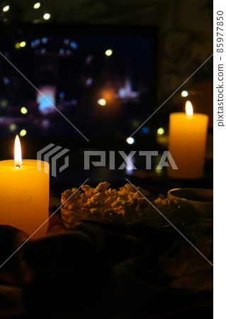Movie on laptop at night in bedroom lit with candles. Pop corn. Autumn atmosphere at home Movie on laptop at night in bedroom lit with candles. Pop corn. Autumn atmosphere at home 85977850