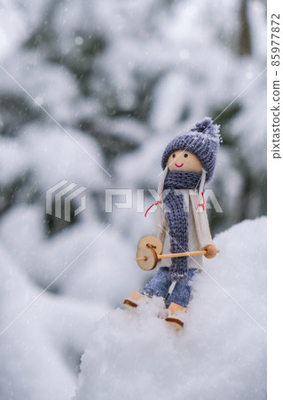 Angel gnome in scarf and knitted hat skiing on snowy fir branch Elf toy on skis in snowy landscape Copy space for text. New year and Merry christmas greeting card background. Ski winter resort 85977872
