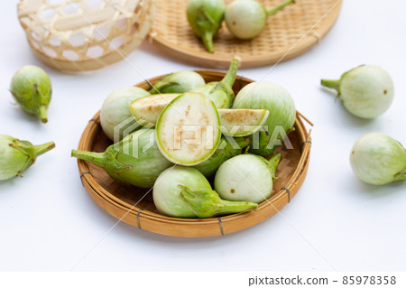 Organic green eggplant in bamboo basket on white background. Organic green eggplant in bamboo basket on white background. 85978358