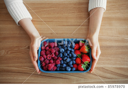 Fresh berries in woman hands. Various summer berries, strawberries, blueberries and raspberries in bowl on rustic wooden background Fresh berries in woman hands. Various summer berries, strawberries, blueberries and raspberries in bowl on rustic wooden background 85978970