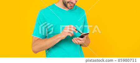 cropped unshaven young man hod phone and stylus on yellow background, technology 85980711