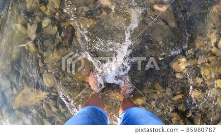 Girl stands barefoot on stones shallow river 85980787