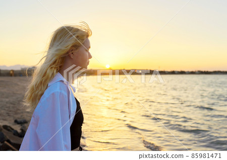 Sea sunset, young woman looking at horizon sun, copy space Sea sunset, young woman looking at horizon sun, copy space 85981471