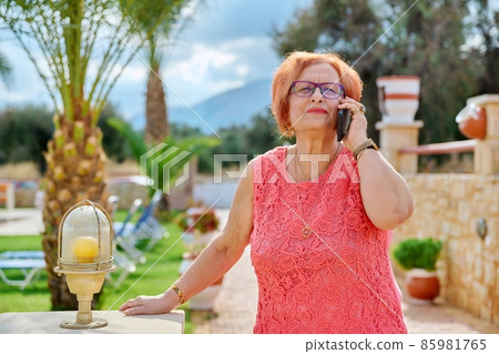 Elderly woman talking on a mobile phone outdoors Elderly woman talking on a mobile phone outdoors 85981765