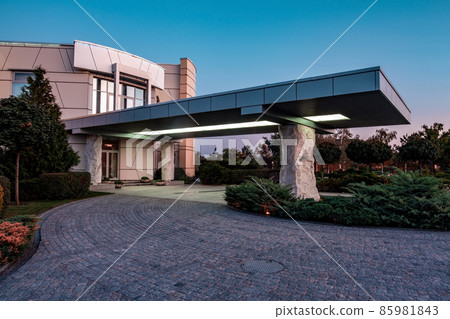 Country mansion with stone pillars supported porch and paved driveway on summer evening Country mansion with stone pillars supported porch and paved driveway on summer evening 85981843