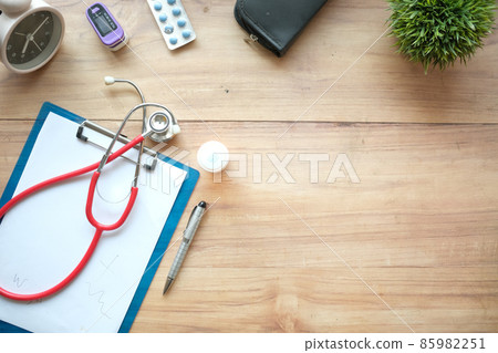 White sheet paper with silver pen, stethoscope and pills on table. 85982251