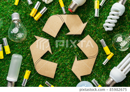 Used metal lithium alkaline batteries and lightbulbs on grass background 85982675