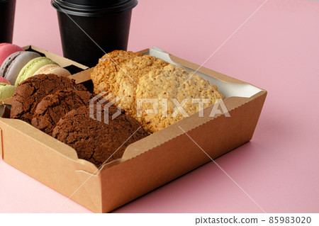 Carton box with oat cookies on pink table Carton box with oat cookies on pink table 85983020