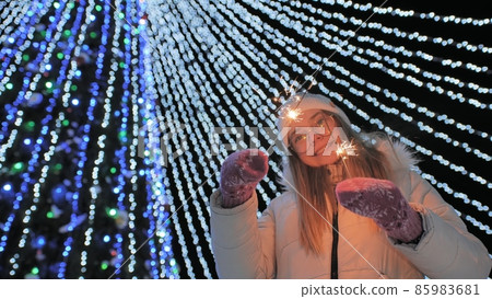 Young girl posing with sparklers against the background of New Year's daisies. 85983681