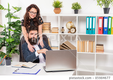 Happy girl embrace man working on laptop at workpalce, office romance Happy girl embrace man working on laptop at workpalce, office romance 85984677