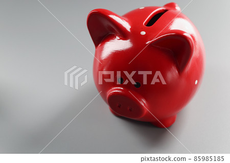 Bright red piggybank container on grey surface, empty thing to put money Bright red piggybank container on grey surface, empty thing to put money 85985185