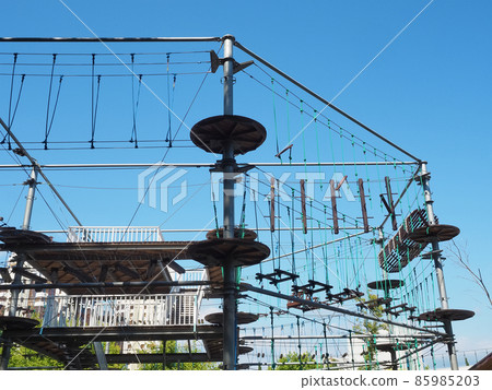 Rope park with wooden beams on metal structures against a cloudless blue sky 85985203