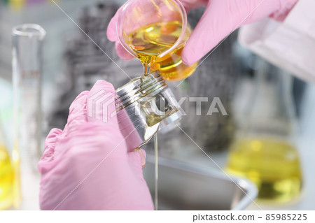 Mans hand in rubber gloves holding car part and pours lubricating oil on it Mans hand in rubber gloves holding car part and pours lubricating oil on it 85985225