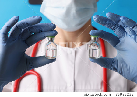Scientist holding two bottles with injection in blue gloves 85985232