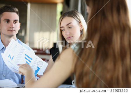Business partners discuss report or contract on meeting in cafe outdoors Business partners discuss report or contract on meeting in cafe outdoors 85985253