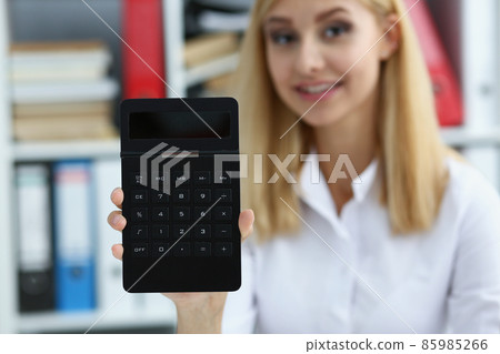 Smiling businesswoman accountant holding calculator in hand demonstrates display Smiling businesswoman accountant holding calculator in hand demonstrates display 85985266