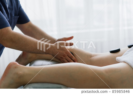 Plump woman getting hot stones arm massage in spa salon. Therapy, wellness and relaxation concept 85985846