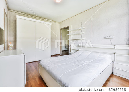 A beautiful bedroom area with a soft bed covered with a blue bedspread A beautiful bedroom area with a soft bed covered with a blue bedspread 85986318