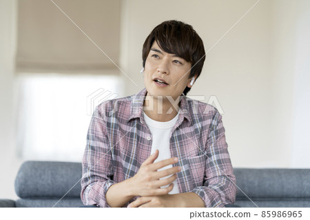 A man in his thirties talking with wireless earphones 85986965