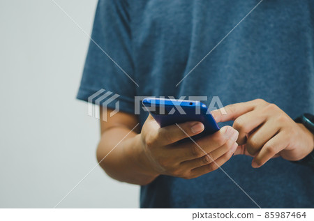 man in a blue shirt is pressing a mobile phone on background. copy space 85987464