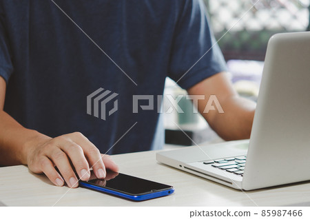man working at computer desk pressing mobile phone 85987466