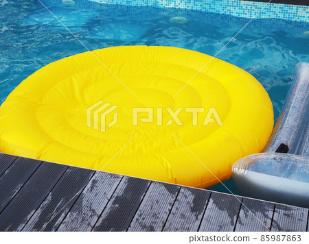 Yellow round inflatable mattress in the blue pool water. Summer rest 85987863