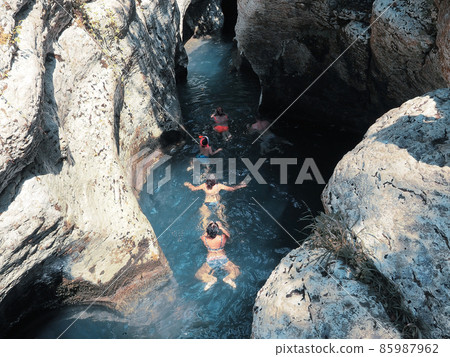 A group of people floats in the rays of the sun along the river flowing into the gorge between the rocks 85987962