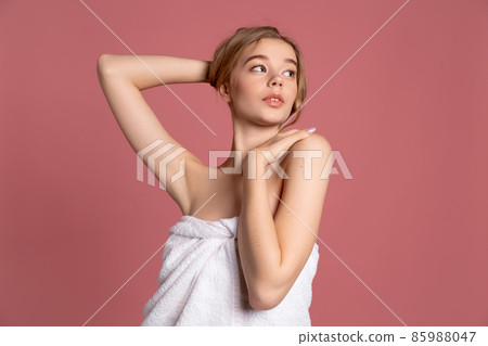 Half-length portrait of young beautiful slim girl in white towel posing isolated over pink studio background. Natural beauty concept. Half-length portrait of young beautiful slim girl in white towel posing isolated over pink studio background. Natural beauty concept. 85988047