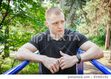 Fit man doing triceps dips on parallel bars at park exercising outdoors. Fit man doing triceps dips on parallel bars at park exercising outdoors. 85988192