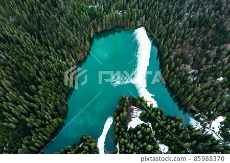 Synevyr lake in the Carpathians, top view of the lake, mountain lake covered with ice, ice line on Synevyr lake. Synevyr lake in the Carpathians, top view of the lake, mountain lake covered with ice, ice line on Synevyr lake. 85988370